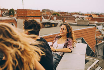 Cheerful young woman enjoying rooftop party with friends on terrace at city