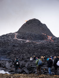 Group of people on rock against mountain range