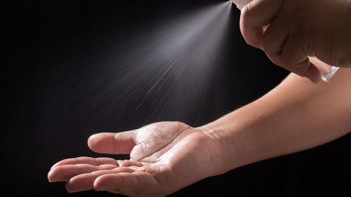 Close-up of man holding hands over black background