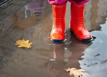 Low section of girl wearing rubber boots while standing in puddle