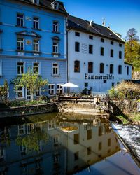 Buildings by river in city against sky