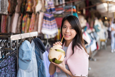 Portrait of woman holding coconut at market