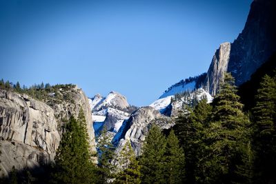 Low angle view of snowcapped mountains against clear blue sky