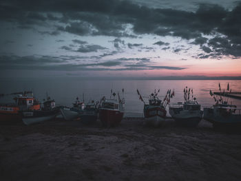 Boats moored at harbor against sky during sunset