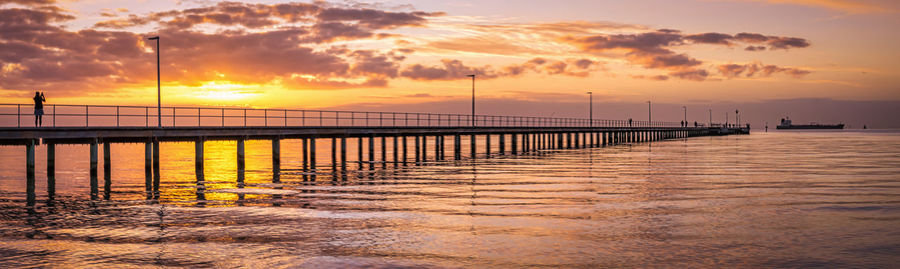 Pier over sea against sky during sunset