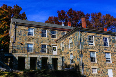 Low angle view of building and trees against blue sky