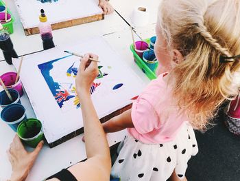 High angle view of mother and daughter making drawing on table