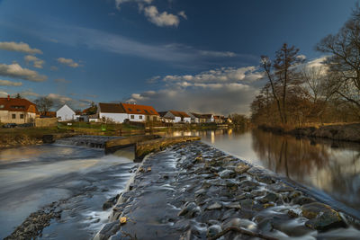 River amidst houses and buildings against sky