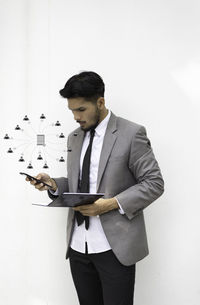 Young man looking away against white wall