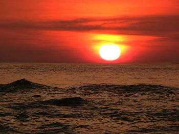 Scenic view of sea against dramatic sky during sunset