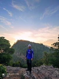 Rear view of man standing on mountain against sky