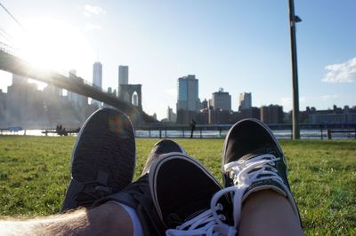 Low section of man relaxing on cityscape against sky