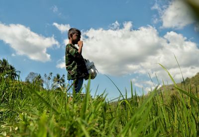 Young man standing on field against sky