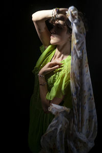 Rear view of woman with arms raised against black background