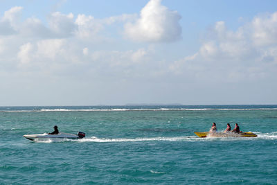 People in sea against sky