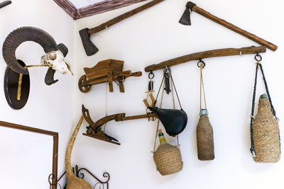 View of wall decorated with old farming implements, axes and ram skull