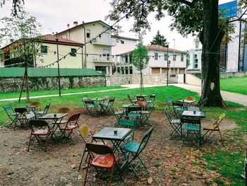 Empty chairs and table on field by building