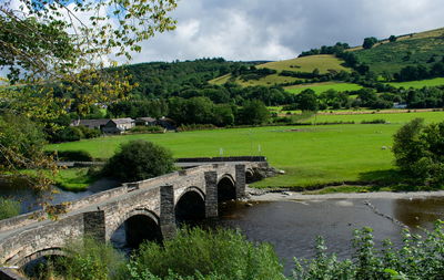 Arch bridge over river against sky