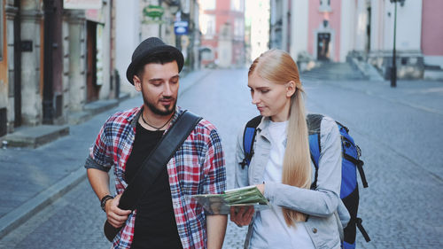Woman holding map while walking with man on street