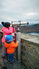 Siblings looking through coin-operated binoculars