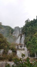 Scenic view of waterfall in forest against sky