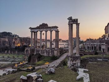 Old building of roman forum in city against sky during sunset