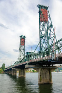 Hawthorne bridge over willamette river against cloudy sky