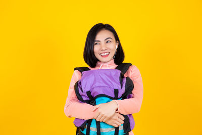 Portrait of a smiling young woman against yellow background