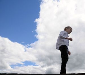 Low angle view of boy standing against sky