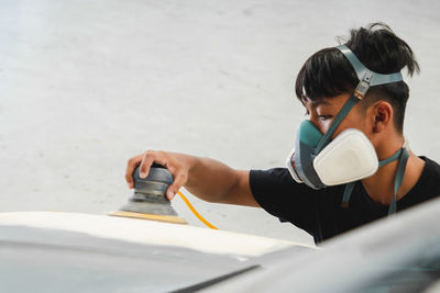 Mechanic wearing mask working on car at garage