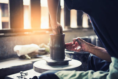 Midsection of woman making pottery in workshop