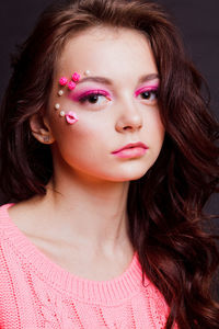 Close-up of beautiful young woman with make-up against gray background