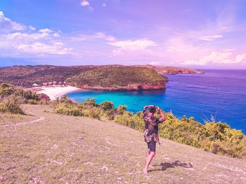 Standing on a hill while looking at the view of the sea and the beach below