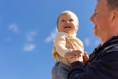 Young father holding cute little daughter in front of blue sky. father day, concept game with child