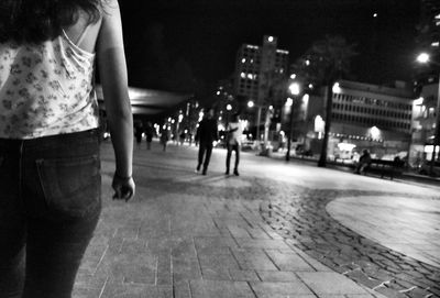 People walking on illuminated street at night