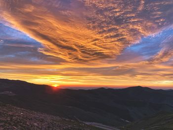 Scenic view of landscape against dramatic sky during sunset