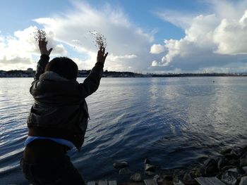 Rear view of people at beach against sky