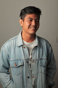 Portrait of smiling young man standing against gray background