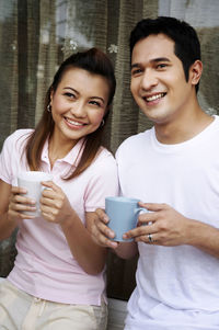 Smiling couple having coffee against wall