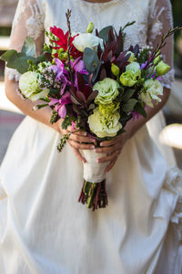 Midsection of bride holding flower bouquet