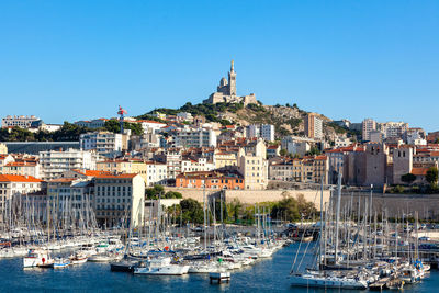 Sailboats moored in harbor against buildings in city