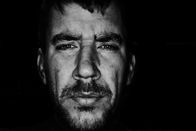 Close-up of bearded man against black background