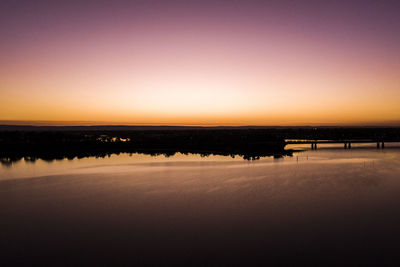 Scenic view of lake against clear sky during sunset