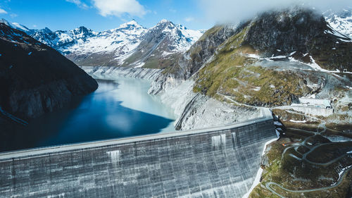 Scenic view of snow covered mountains against sky with a dam