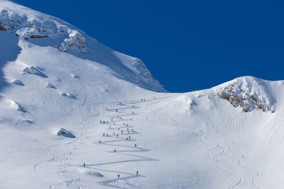 Scenic view of snowcapped mountains against clear blue sky