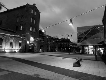 Illuminated street amidst buildings in city at night