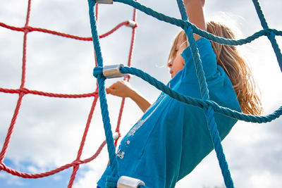 Low angle view of woman standing on rope against sky