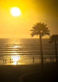 Silhouette palm trees on beach against clear sky at sunset