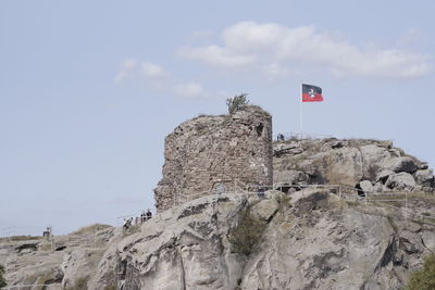 Low angle view of flag on rock formation against sky