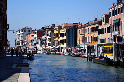 Buildings by canal against clear sky in city